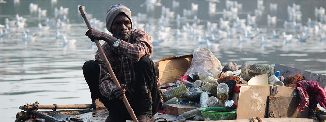 fishermen on boat collecting plastic waste from a river